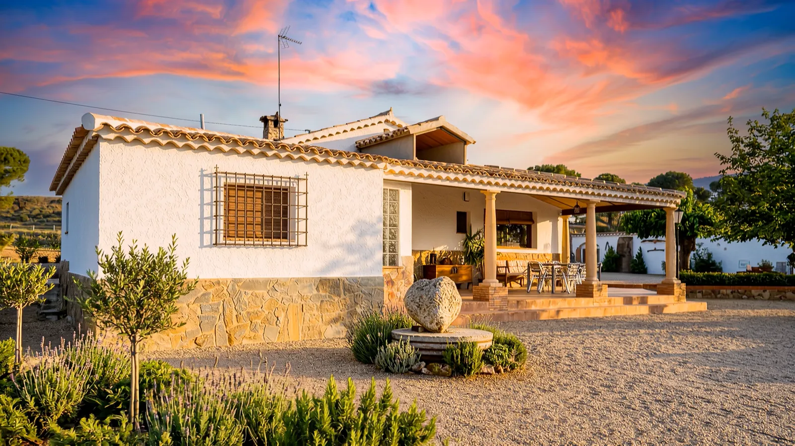 La casa de El Cadillar al atardecer, con el porche y el jardín de lavanda